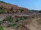 stock photo of a dry river surrounded by majestic mountains under bright sunlight, blue sky on background. Pictured captured at