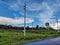 Stock photo of empty roadway along with electric pole with power transmission line on the left side of the road. old rusty water