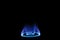 Stock photo of gas burner with blue flame on kitchen stove in dark black background, focus on object