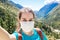 Stock photo of a girl with face mask selfie photo in the mountain and a beautiful landscape in the background