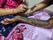 Stock photo of henna artist applying or drawing henna design on hand of bride with piping cone for traditional mehnadi ceremony in