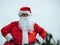 Stock photo of Santa Claus standing with arms resting on his hips grabbing his red bag. Christmas time