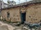 Stock photo of traditional clay made house with old damage clay made roof tile, cracks on mud wall and blue painted wooden door.