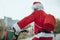 Stock photo of the view of Santa Claus` back with bicycle and his red suitcase on his back. Christmas time