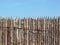 Stockade wooden fence on blue sky background