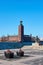 Stockholm city hall in daylight against a blue sky with waves on water.