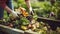 stockphoto, Person composting food waste in backyard compost bin garden. Person putting green waste into a compost bin