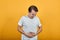 Stomach pains stomach problems white T-shirt young male on yellow background.