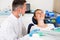 Stomatologist in uniform is taking visional inspection of a girl on the chair