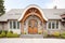 stone accented shingle house with arched wooden doors