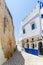 Stone alley with historic city wall and white and blue washed buildings in Asilah, Morocco, North Africa