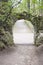 Stone arch surrounded by foliage of trees. Beautiful arch of rough bricks, vertical