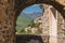 Stone archway overlooking the rolling hills and quaint villages in Castelvecchio di Rocca Barbena