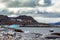 Stone arctic coast, motorboat and blue iceberg floating in the b