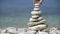 Stone balance closeup. Female hand making pebbles tower from sea stones. Macro of pyramid of pebbles on beach.