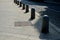 Stone barriers in a square shaped cylinder with a hemisphere on top. granite curbs as stops at the parking lot. chain decorative f
