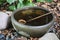 Stone basin filled with water and a wooden spoon, placed on the floor