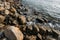 Stone beach at sea shore, close up. Ocean water waves at sunset, relaxation and tranquil nature background