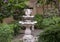 Stone birdbath surrounded by hibiscus flowers and green vegetation at outside First Baptist Church of Arlington.