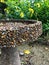 Stone birdbath with yellow wildflowers in garden