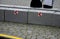 Stone blocks connected by metal strips. The unit acts as a road barrier with traffic arrows in a bend. A heavy chain protects the