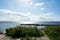 Stone breakwater on a coast in the sea, with a sailing ship on the horizon and a bright sun