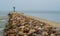 Stone breakwater with green lighthouse in a small harbor