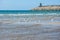 Stone breakwater, sandy beach, blue sea.