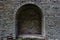 Stone brick antique arch is a window. Northern Europe, the castle. Fortress wall made of gray bricks.
