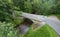 Stone bridge crosses a stream in Eagle mountains Orlicke hory during summer time.