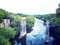 Stone bridge pilings in the river surrounded by green vegetation.