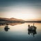 Stone building and tree stumps reflected in lake at dusk