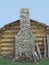 Stone chimney on wall of log cabin.