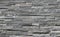 Stone cladding wall made of  striped stacked slabs of natural dark gray rocks. Panels for exterior .