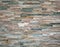 Stone cladding wall made of striped stacked slabs of natural rocks.. Colors are various, from dark green to white.