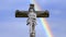 Stone cross with Jesus and blue sky with rainbow