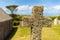 A stone cross overgrown with moss in the sunshine in Cornwall.