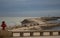 Stone dam with lighthouse. Long pier on coast in the evening. Embankment on tropical seaside. Coastline in cloudy evening.