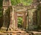 Stone doorway guarded by two warrior statues at Ta Prohm temple ruins, located in the Angkor Wat complex near Siem Reap, Cambodia.