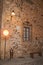 Stone facade with lamp, barred window, bench and transit sign at dusk in Caceres