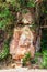 Stone face of Buddha by the Picturesque road in mountains of National park Bokor leading to Abandoned hotel Bokor Palace in Ghost