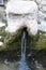 Stone face fountain with water in detail