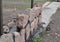 Stone fence construction: A close-up on a stone masonry fence foundation building on a concrete bed using a level line