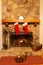 A stone fireplace with two Christmas stockings hung on the mantle and the family cat relaxing by the fire.