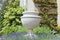 Stone flowerpot in an english landscaped garden, summertime .