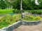 Stone,flowers and trees in a park where you can rest if you want to.