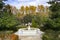 Stone fountain with trees and autumn vegetation around it. Next to the Royal Palace of Madrid, in Spain. Europe.