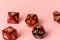 Stone gaming dice different shapes on pastel pink background. Top view