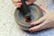 Stone Grinder Bowl. Woman Hands Grinding Pepper In Stone Mortar.