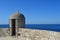 A stone guard tower overlooking a blue sea